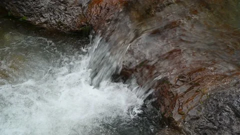 Clear water flows over rocks into a pool Stock Footage 211457899