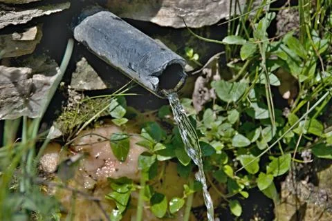 Clear water flows from a pipe Stock Photos