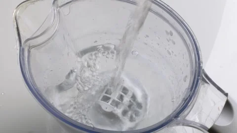 Clear water flows into plastic filter jug on white background, symbolizing eco Stock Footage 305772661