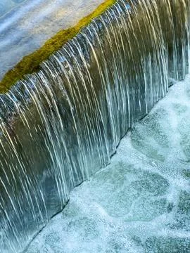 Clear water flows softly over a moss-covered stone ledge. Bubbles form as the Fotos Stock