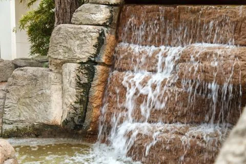 Clear water flows through an artificial waterfall cascade 스톡 사진