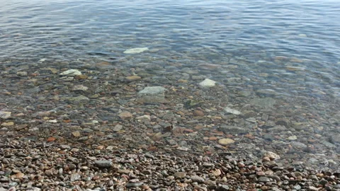 Clear water in the lake. Small waves on the pebble beach Video stock 307890094