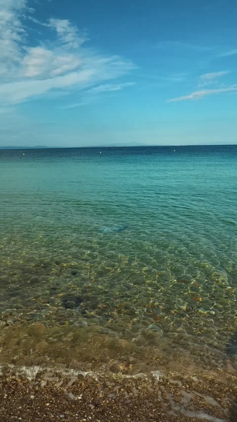 Clear water laps gently at pebbled shore. Nikiti, Greece. Vertical Video stock 339025510
