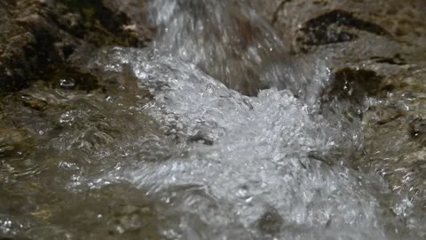 Clear water from a mountain river flows and creates bubbles (slow motion) Video stock 212729143