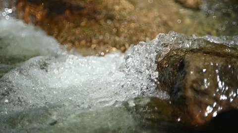Clear water from a mountain stream runs over a stone (slow motion, bokeh) Stock-Footage 219390199