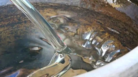 Clear Water Pouring into Rust-Textured Metal Barrel or Container Video stock 343587703