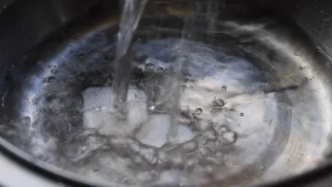 Clear water pours into a metal basin. Close-up view. Water being poured int.. Stock Footage 341343473