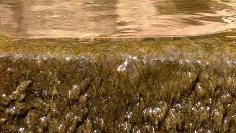 Clear water running over the edge and down the wall of a stone tub Stock Footage 76820590