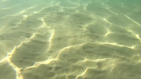 Clear water shows light patterns on the sandy floor at a tropical beach in summe Stock Footage 335333648