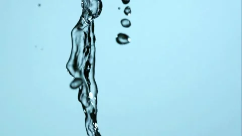 Clear water stream falls vertically against a blue background in slow motion Stock Footage 326624797