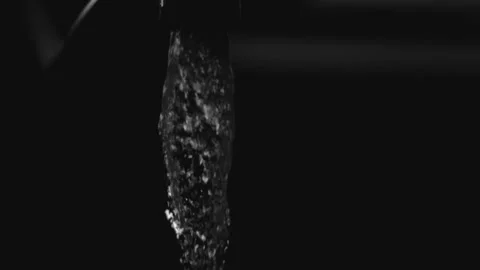 Clear water stream pouring down against a black background Stock Footage 327514129