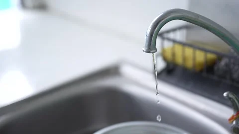 Clear water streaming smoothly from a metal faucet Stock Footage 344704532