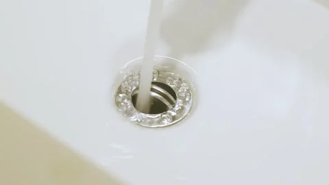Clear Water Swirling Down White Ceramic Sink Drain, Close-up Stockbeeldmateriaal 336563685
