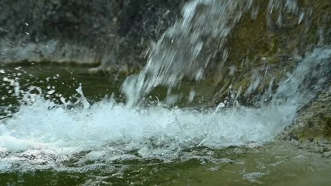 Clear water from a waterfall is falling into a natural pool (slow motion) Video stock 211761144