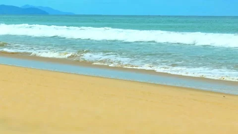Clear water waves break on the sandy beach under a blue sky. Stock Footage 308054815