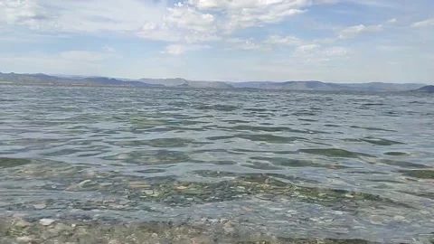 Clear water. Waves. The mountains. Clouds. splash. Stones at the bottom. Stock Footage 335458689