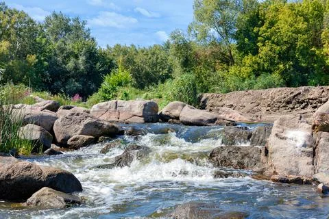 The clear waters of a forest stream make their way through the large stone bo Stock Photos