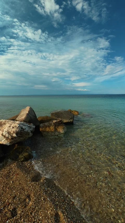 Clear waters lap soft stones along a calm shoreline. Nikiti, Greece. Vertical 库存影片 339025509