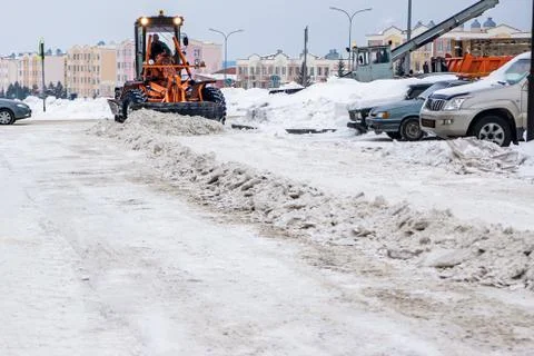 Clearing compacted snow from the road using heavy snow removal equipment and  Stock Photos
