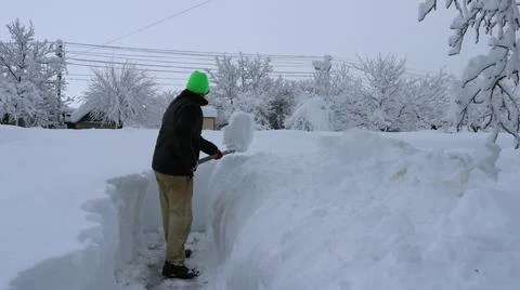 Clearing a path through heavy snow from the house to the road. Stock Photos
