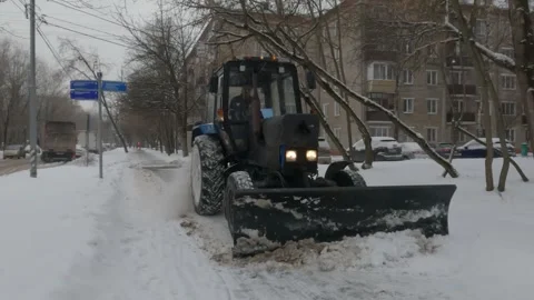 Clearing the sidewalk from snow after a snowfall with a tractor Stock Footage 258844737