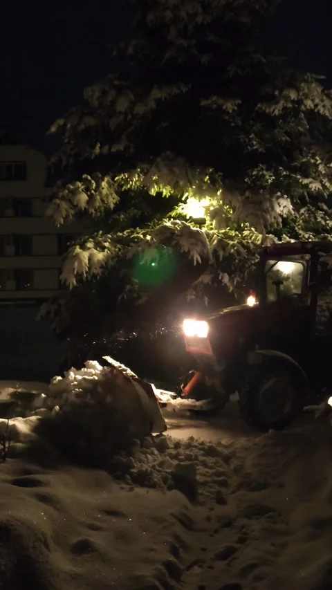 Clearing snow from roads with a tractor in the evening Video stock 325674814