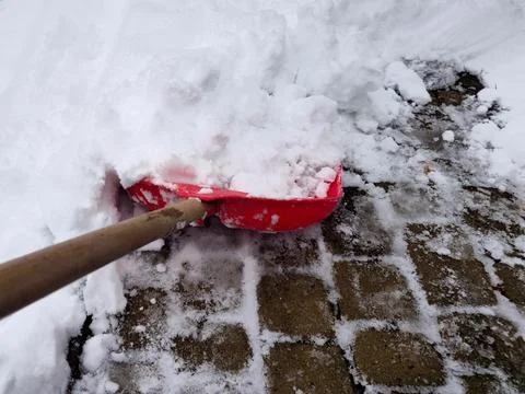 Clearing snow from the sidewalk with a red plastic shovel in winter. Cleani.. Foto stock
