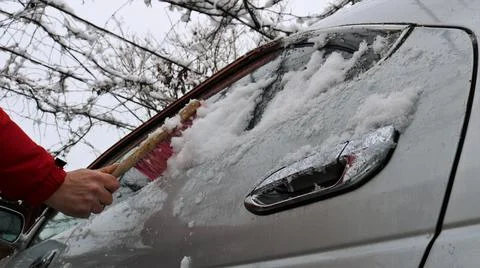 Clearing snow from a silver car window Stock Photos