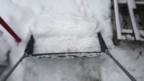 Clearing snow with snow scoop from yard Stock Footage 146884090