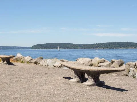 Cleat-shaped stone benches along the rocky coast of Puget Sound in Ruston, WA Stock Photos