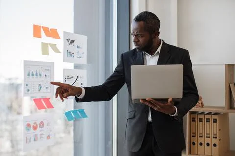 Clerk examining data on computer and diagrams on board Stock Photos