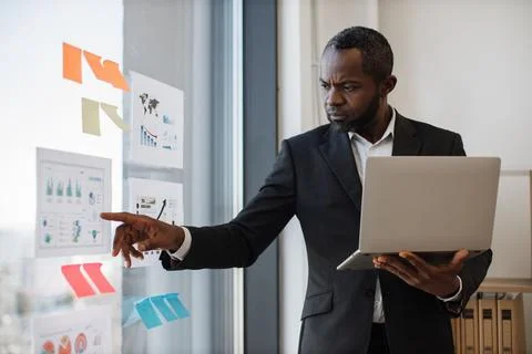 Clerk examining data on computer and diagrams on board Stock Photos