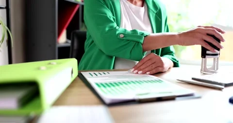 Clerk prepares approval of document using stamp on sales report before sending Stock Footage 218582695