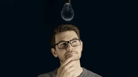 Clever creative man think gets an idea, which lights up a symbolic lamp over his Stock Footage 74409436