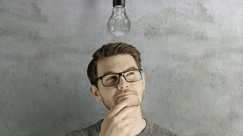 Clever creative man think gets an idea, which lights up a symbolic lamp over his Stock Footage