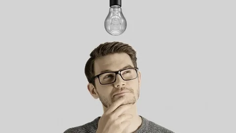 Clever creative man think gets an idea, which lights up a symbolic lamp over his Stock Footage 74409981
