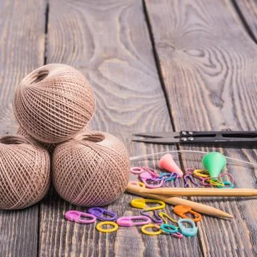 Clews of yarn, knitting needles, scissors and clips on wooden background. Stock Photos