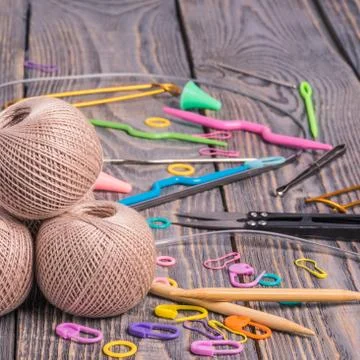 Clews of yarn, knitting needles, scissors and clips on wooden background. Stock Photos