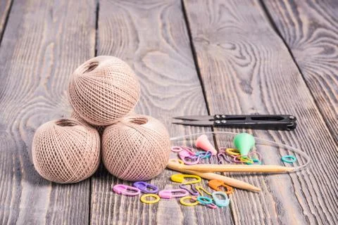 Clews of yarn, knitting needles, scissors and clips on wooden background. Stock Photos