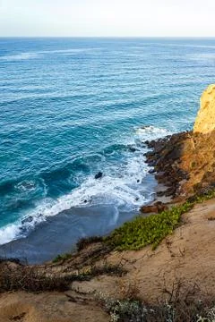 Clff side view of pacific ocean wavy shore and rocks, from sandy iceplant edged Stock Photos