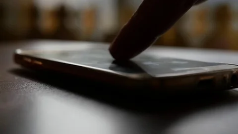 Click on the phone screen, which lies on the table with a blurred background. HD Stock Footage 81714349
