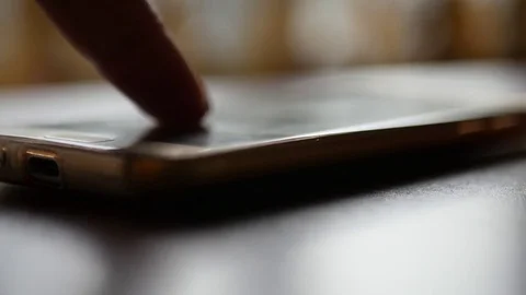 Click on the screen of the smartphone that lies on the table. 3840x2160, 4K Stock Footage 81714370