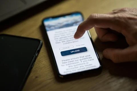 Clicking on upload button on smartphone app Stock Photos