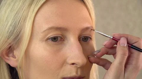 A client in a beauty salon does makeup. the makeup artist draws the eyebrow Stock Photos