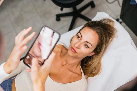 Client capturing lip micropigmentation procedure on smartphone for social media Stock Photos