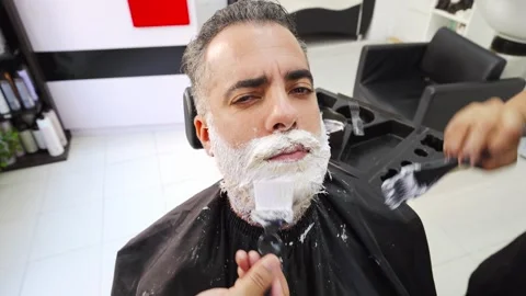 Client in hairdressing shop making faces during beard dyeing process 스톡 동영상 255795925