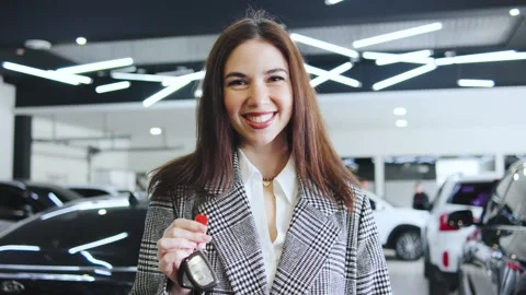 Client holding car keys and celebrates new car purchase with saleswoman in Stock Footage 320738044