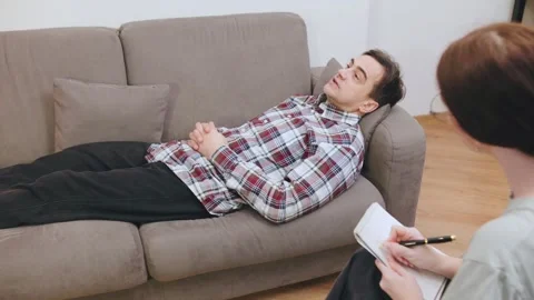 Client lays on couch during a therapy session while the psychotherapist takes Stock Footage 318153659