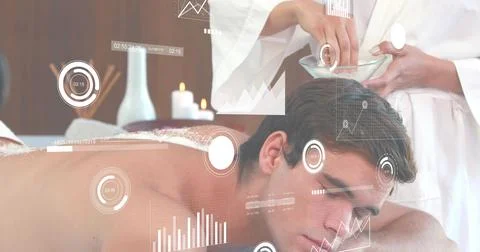 Client lying prone in spa with white towel, therapist in white robe prepping Stock Photos