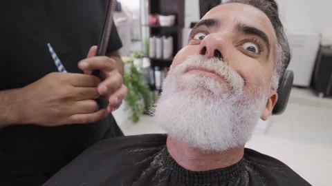 Client making faces while getting his beard shaped by stylist.MOV 스톡 동영상 255795814